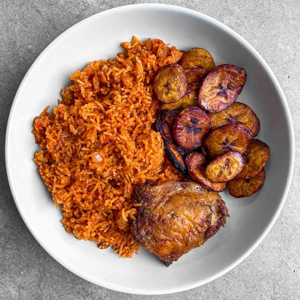 Bowl of jollof rice with plantain and chicken